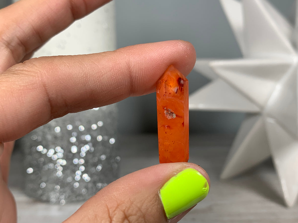 Hand holding Mini Carnelian Crystal Tower for energy and trust on natural background