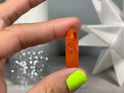 Hand holding Mini Carnelian Crystal Tower for energy and trust on natural background