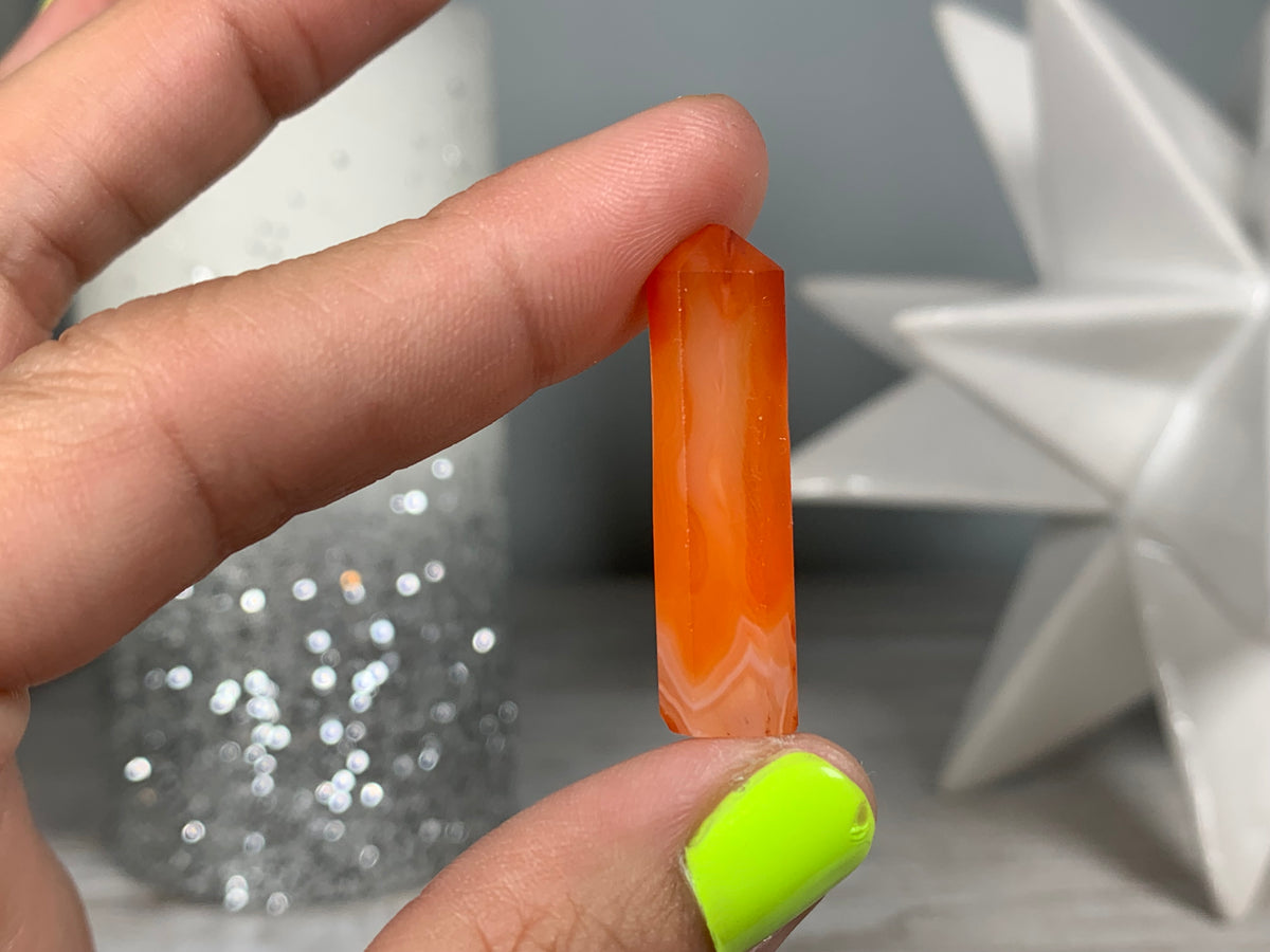 Hand holding Mini Carnelian Crystal Tower for energy and trust on natural background