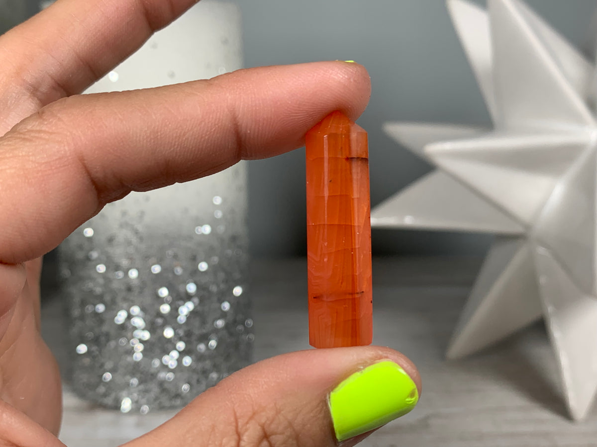 Hand holding Mini Carnelian Crystal Tower for energy and trust on natural background