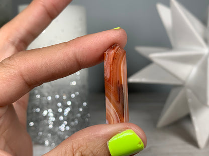 Hand holding Mini Carnelian Crystal Tower for energy and trust on natural background