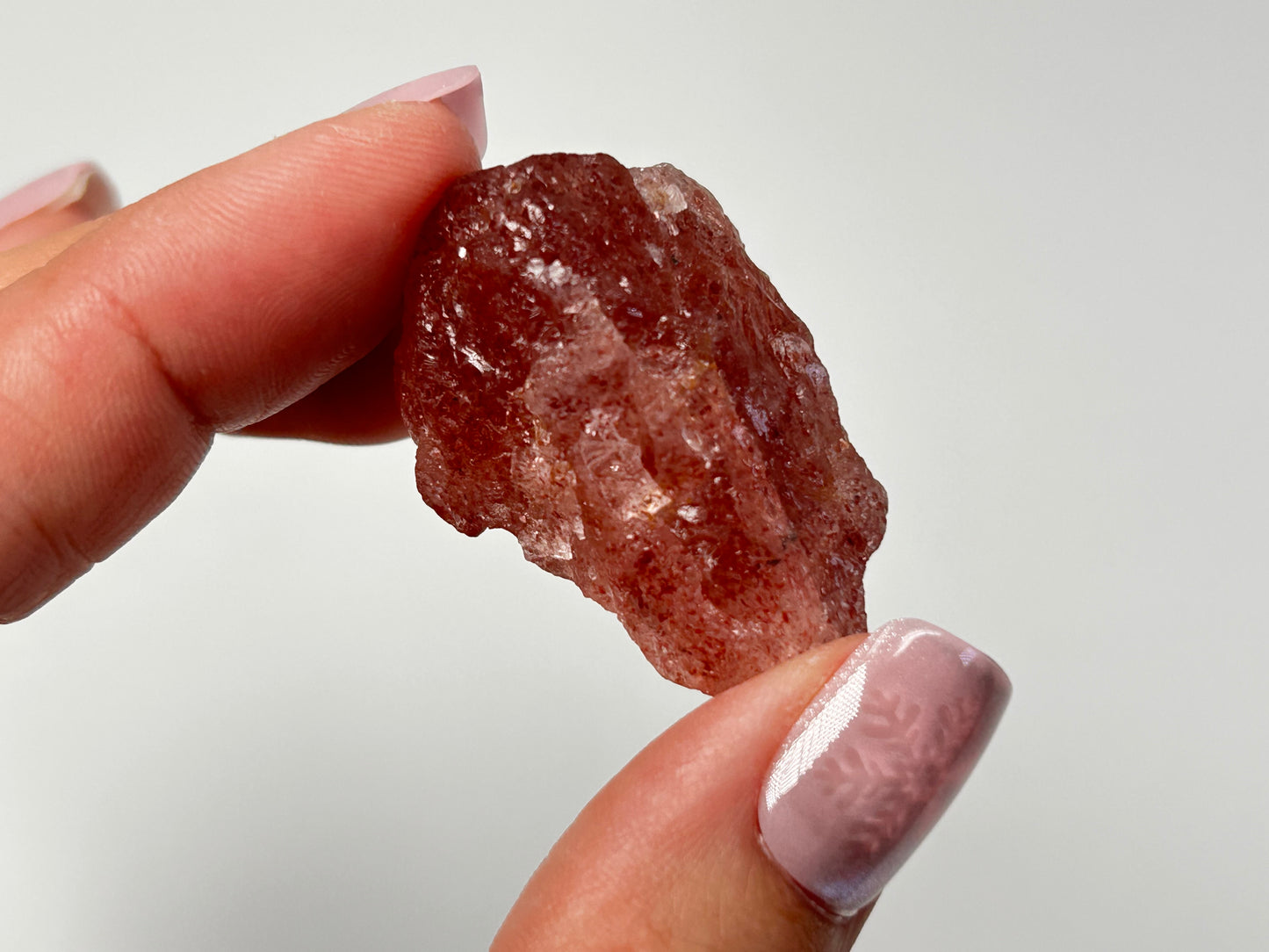 Hand holding Natural Cherry Quartz Tanzurine Chunk for meditation and energy work with white background.