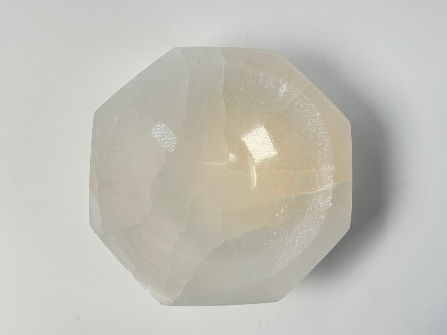 Octagon Selenite Bowl from Morocco for energy healing on table with white background. 
