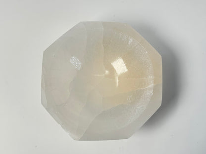 Octagon Selenite Bowl from Morocco for energy healing on table with white background. 
