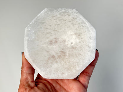 Hand holding a Octagon Selenite Bowl from Morocco for spiritual healing against white background