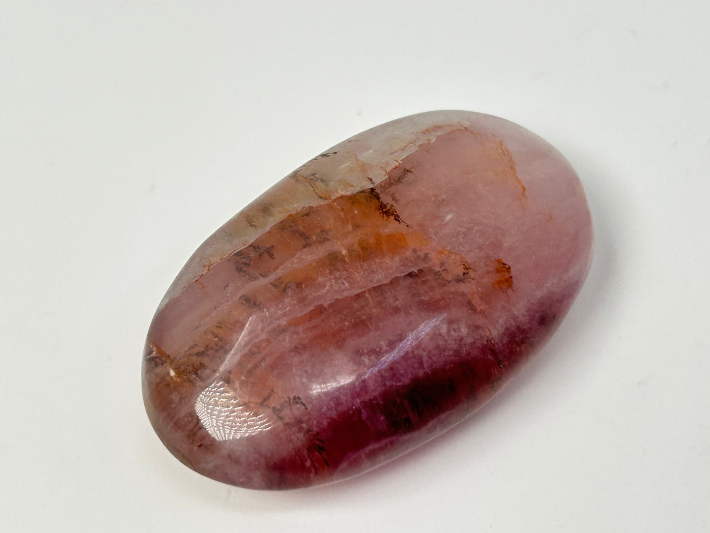 Oval-shaped Brown Organic Dendritic Fluorite Palm Stone healing gemstone on table with white background.