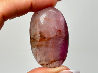 Hand holding a Oval-shaped Brown Organic Dendritic Fluorite Palm Stone healing crystal gemstone for meditation and energy work with white background.