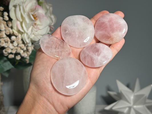 Polished Rose Quartz palm stone crystals for love, compassion, healing, Reiki charged, person holding three flat, polished rose quartz stones in their hand.