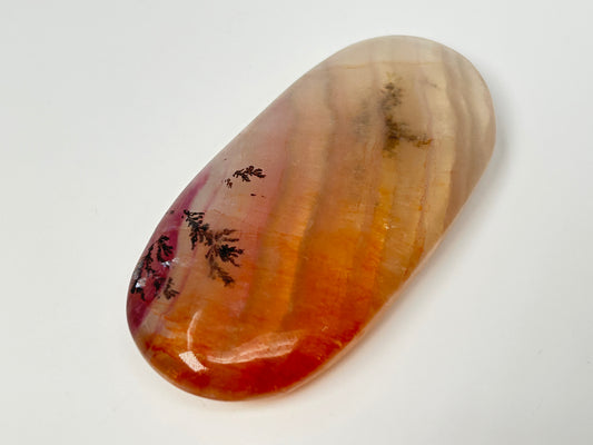 Polished, oval-shaped light-brown Dendritic Fluorite mineral palm stone with brown and orange colored markings reminiscent of a landscape meditation healing crystal ethically sourced gemstone.on a white background