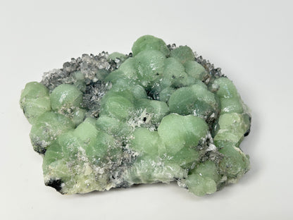 Prehnite on Quartz Cluster natural grounding crystal on table with white background. 