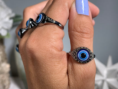 Close-up of hand with Protect Your Peace Silver Evil Eye Rings for energy and trust against a white gray floral background