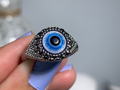 Close-up of hand with Protect Your Peace Silver Evil Eye Ring for energy and trust against a white gray floral background