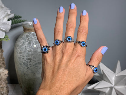 Close-up of hand with Protect Your Peace Silver Evil Eye Rings for energy and trust against a white gray floral background