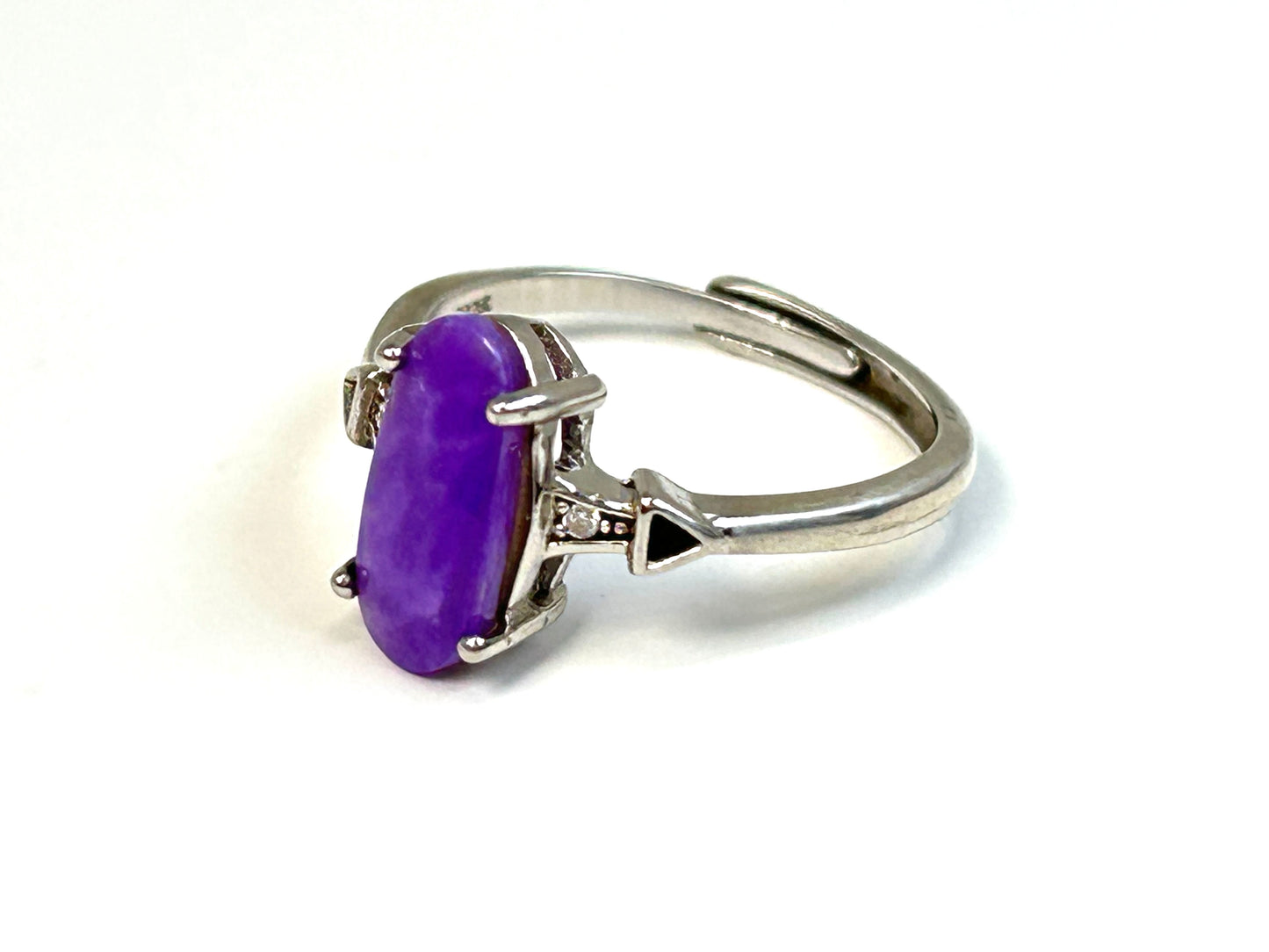 Purple Sugilite Crystal in Sterling Silver Ring with Cubic Zirconia on table stand with white background.