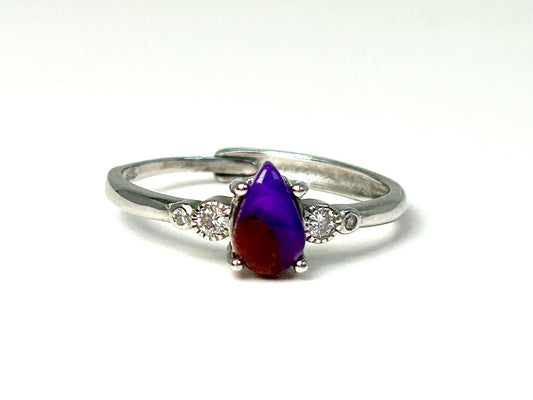 Purple and red Sugilite Ring with Cubic Zirconia in Sterling Silver on table with white background.