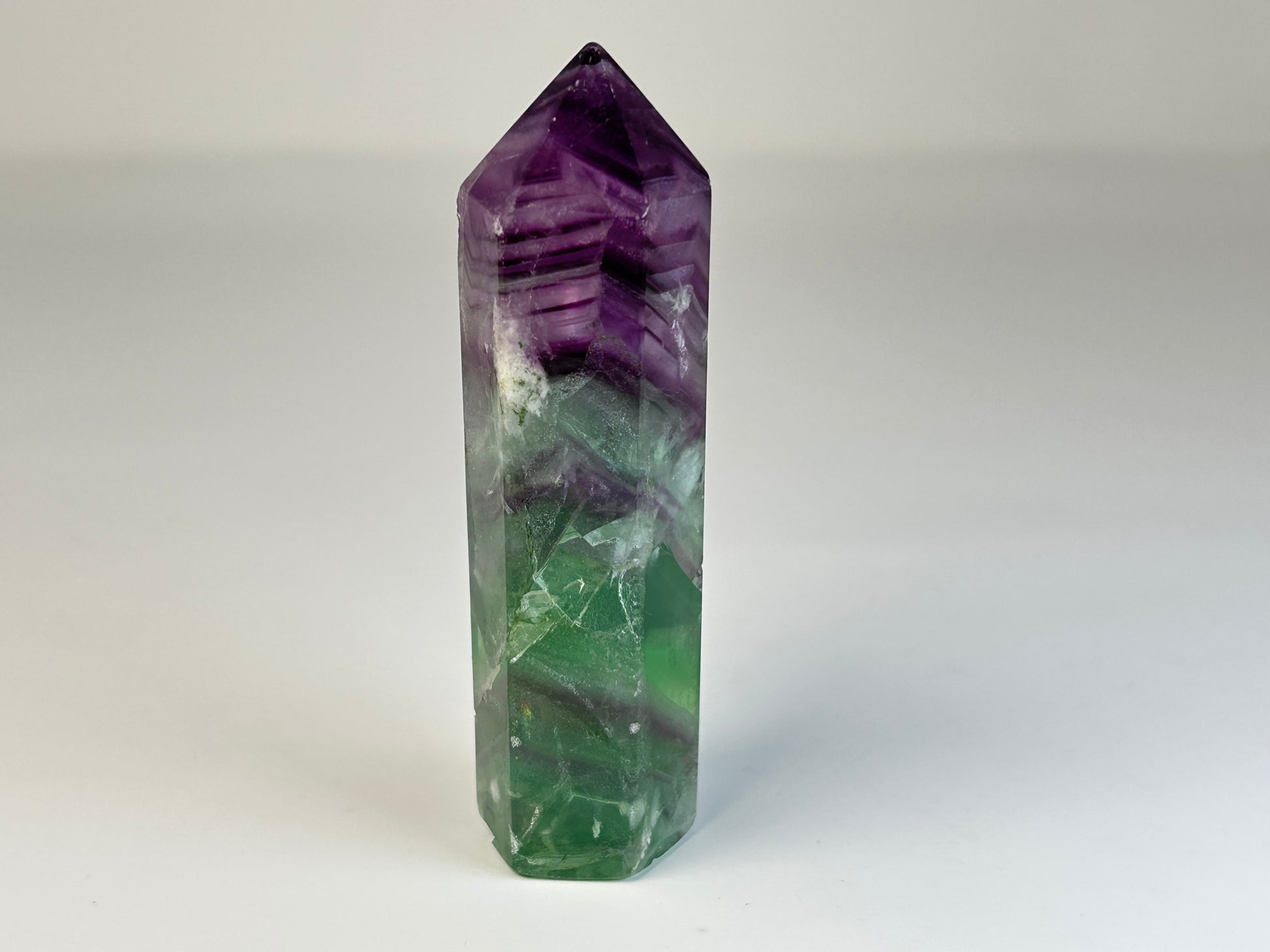 Rainbow Fluorite Tower gemstone for natural grounding on table with white background 