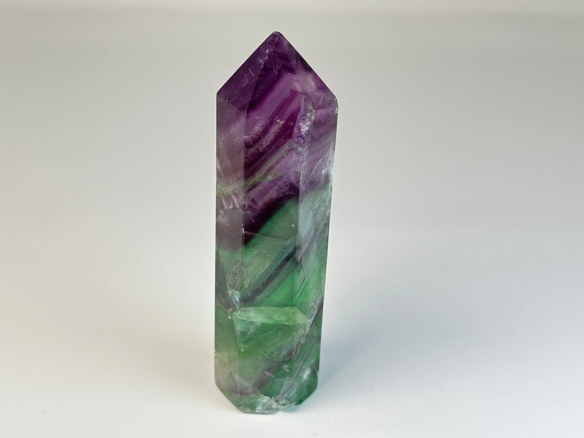 Rainbow Fluorite Tower gemstone for natural grounding on table with white background 