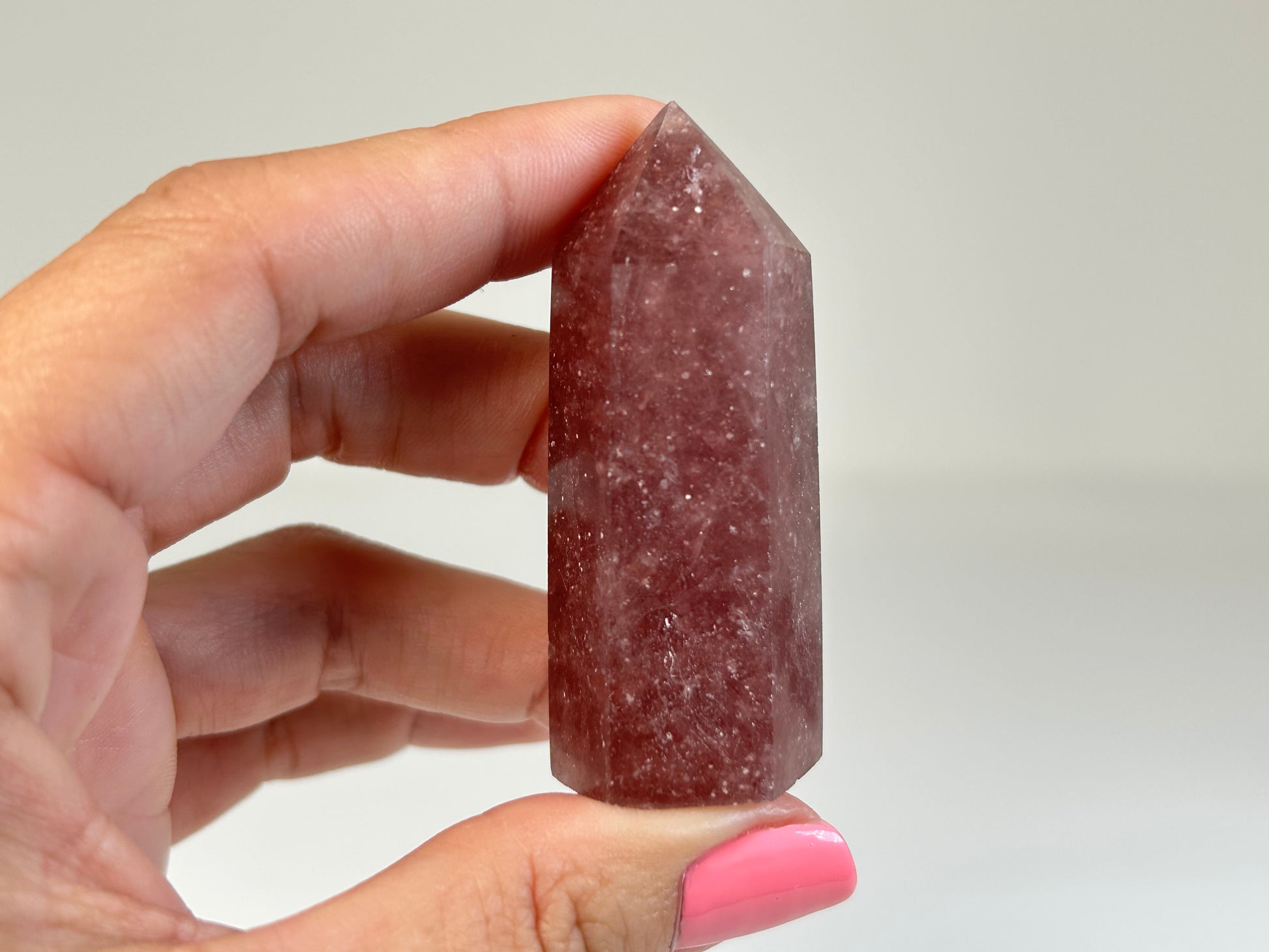 Hand holding a Red Aventurine Crystal Tower against a plain background