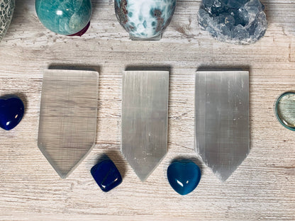 Selenite Flat Point Crystals for energy and trust with white gray floral background.