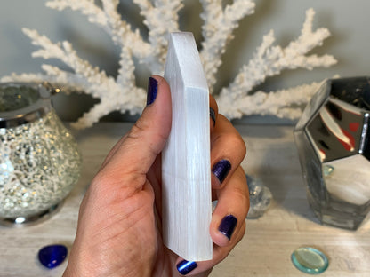 hand holding Selenite Flat Point Crystals for energy and trust with white gray floral background.