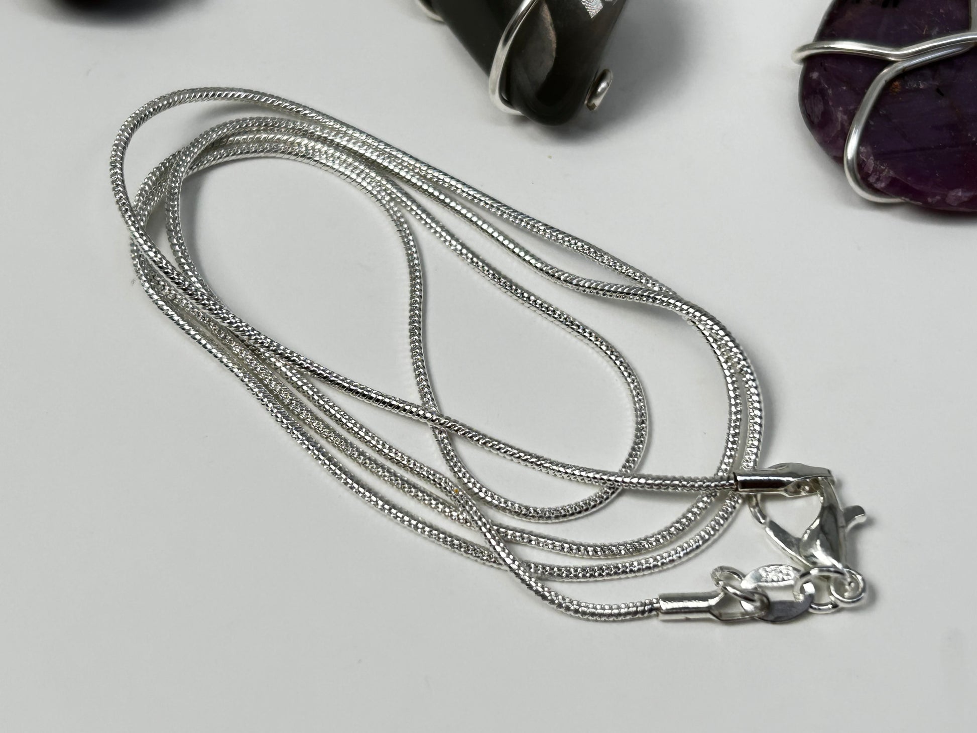 Silver necklace for Wire Wrapped Crystal Pendants for emotional spiritual and physical balance on white table. 
