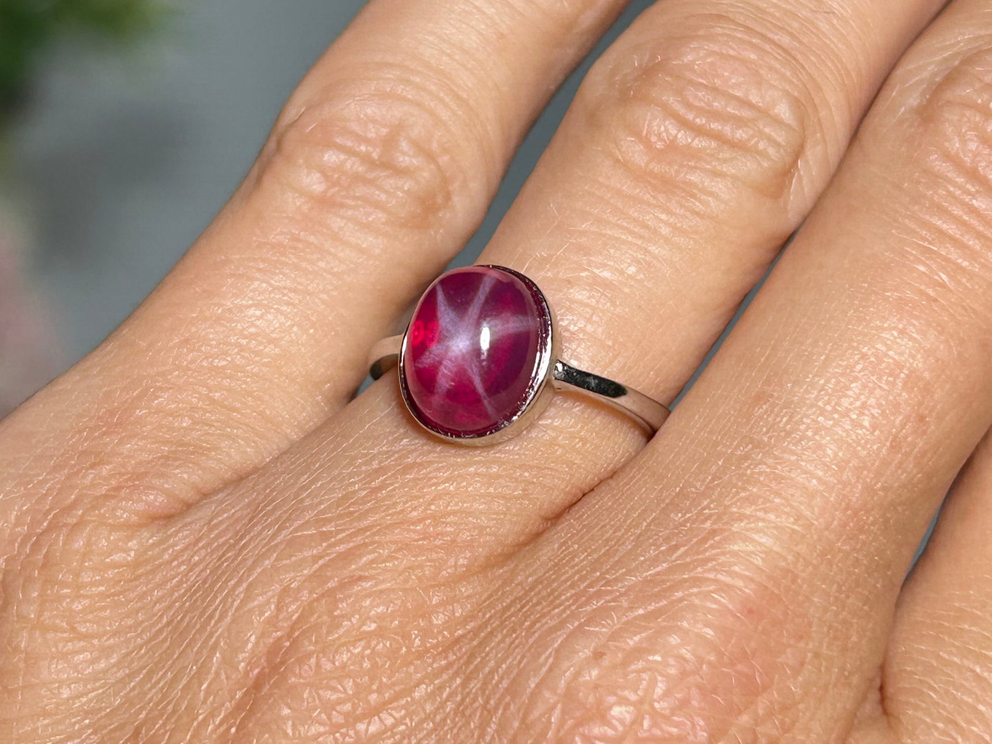 Close up of a finger wearing a Star Ruby Ring in Sterling Silver for meditation and energy work with white background