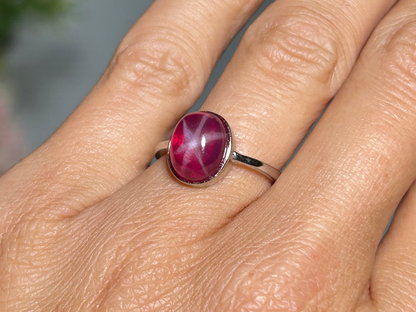 Close up of a finger wearing a Star Ruby Ring in Sterling Silver for meditation and energy work with white background