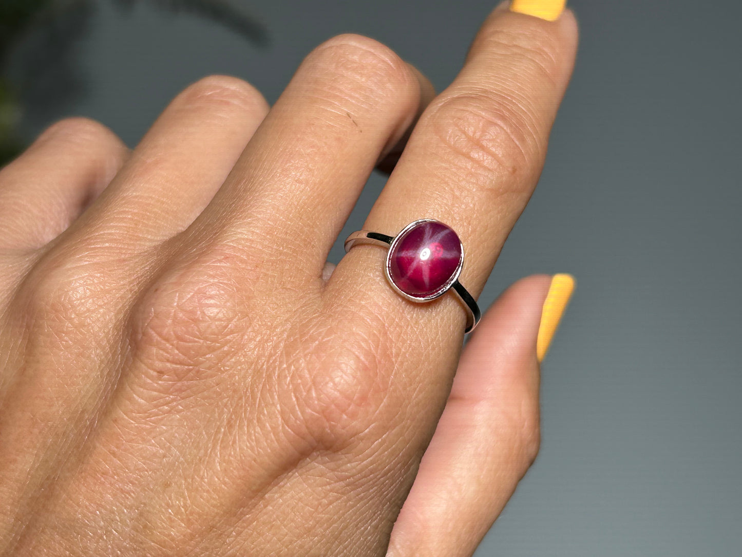 Hand wearing a Star Ruby and Sterling Silver Ring for natural grounding crystal healing stone with white background