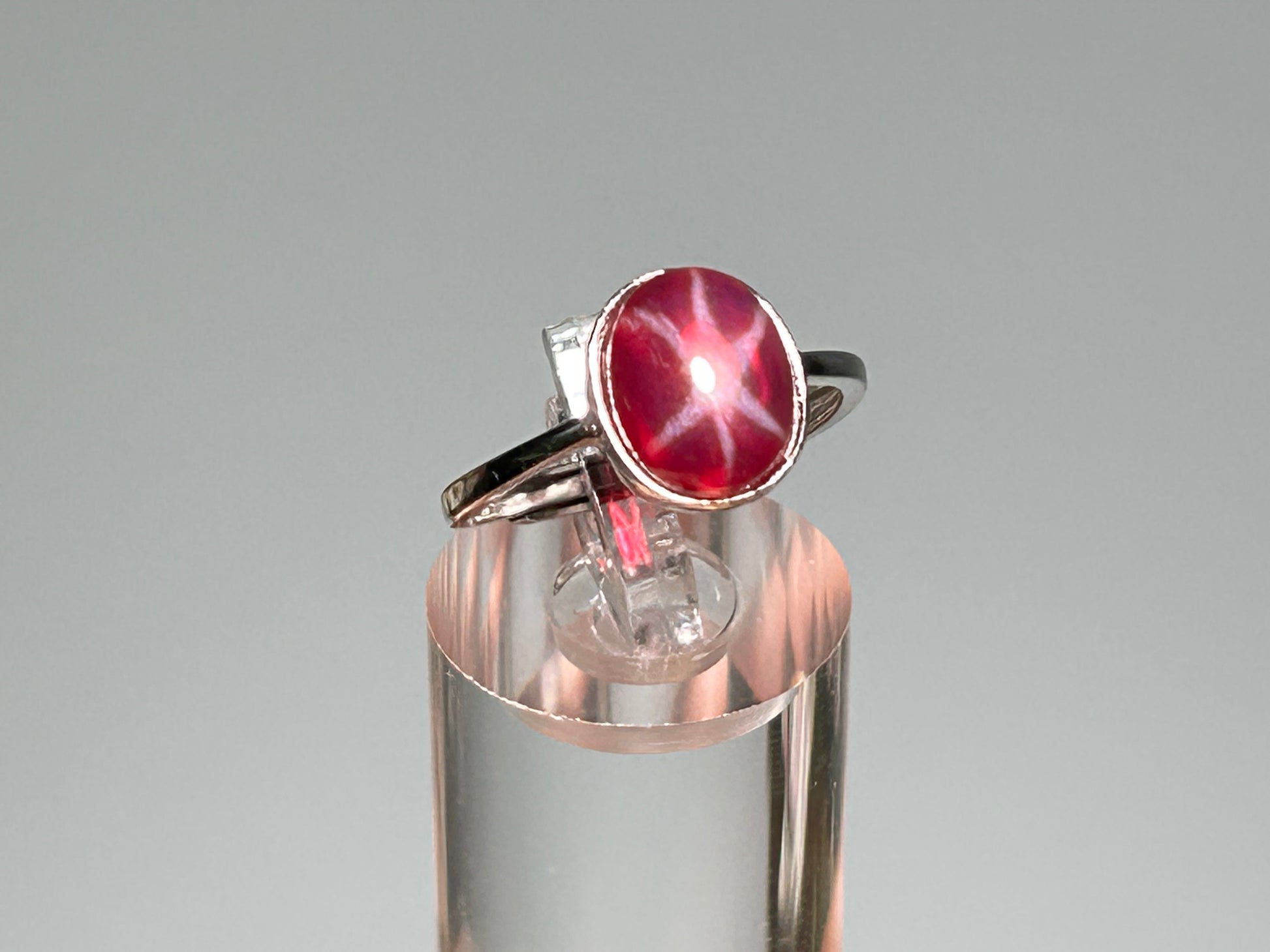 Star Ruby and Sterling Silver Ring on table stand with gray background.