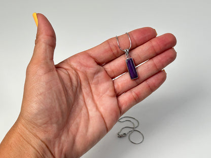 Hand holding a Sugilite Sterling Silver Pendant for meditation and energy work with white background