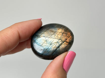 Hand holding a Labradorite stone with a gray background