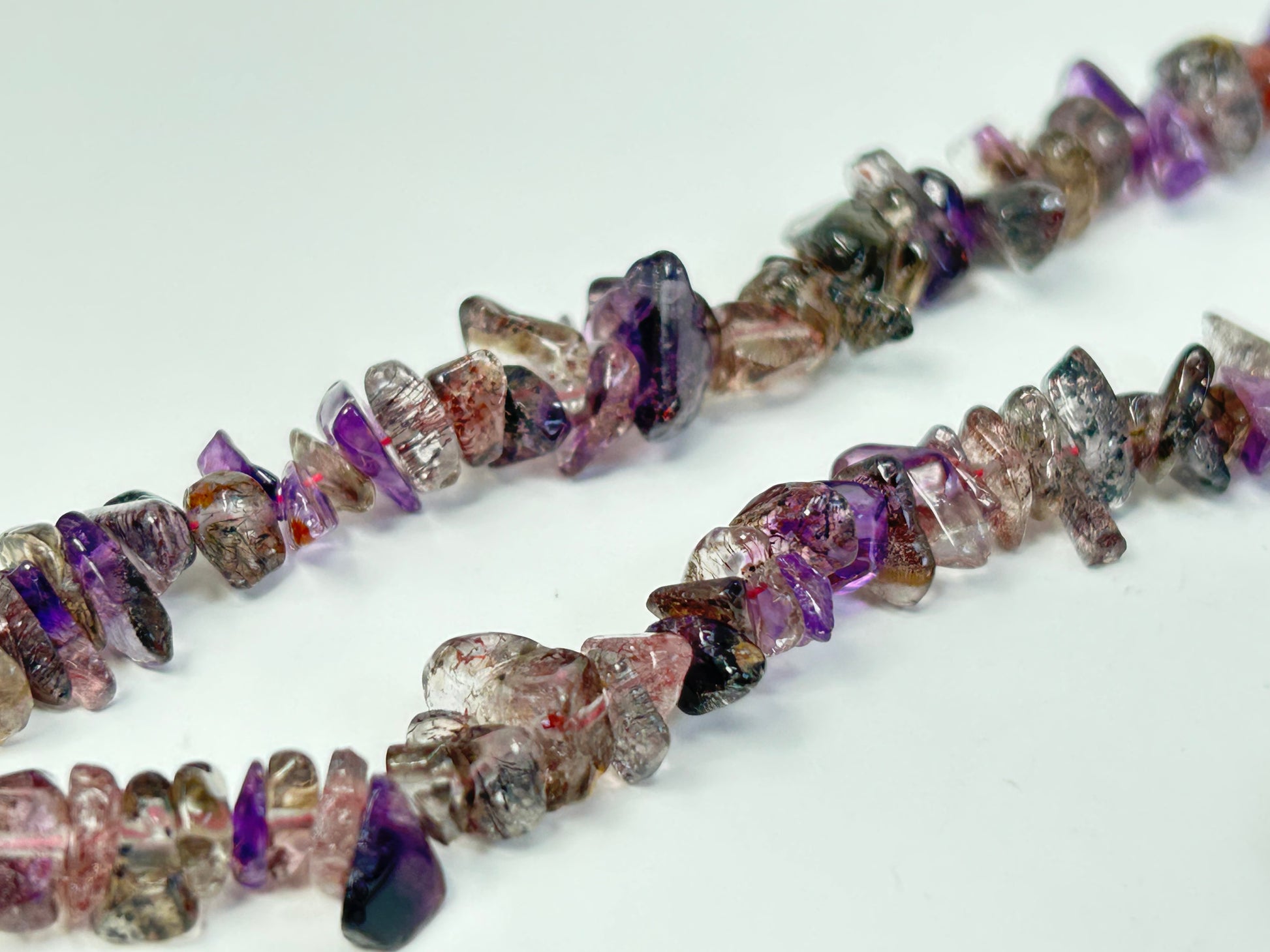 A Super 7 Chip Bead Bracelet with multicolored gemstone chips on a white background