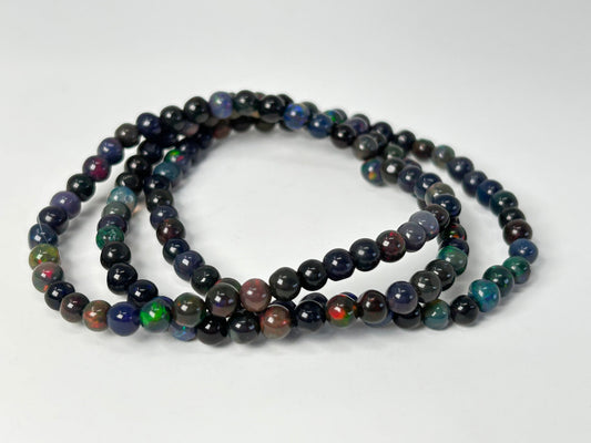Three Transformative Black Opal Bracelets with multicolored stones on a white background