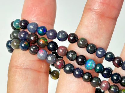 hand holding Multicolored Transformative Black Opal Bracelets on a white background