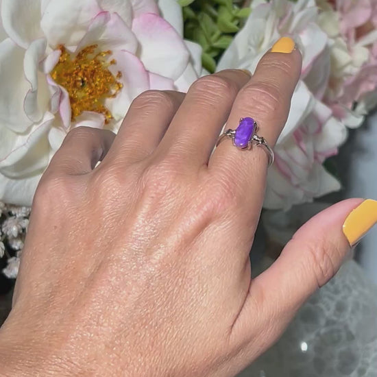 Video of hand wearing a Purple Sugilite Crystal in Sterling Silver Ring with Cubic Zirconia with white gray and floral background.