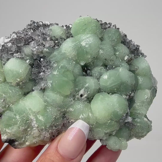 Prehnite on Quartz Cluster healing gemstone on table with white background.