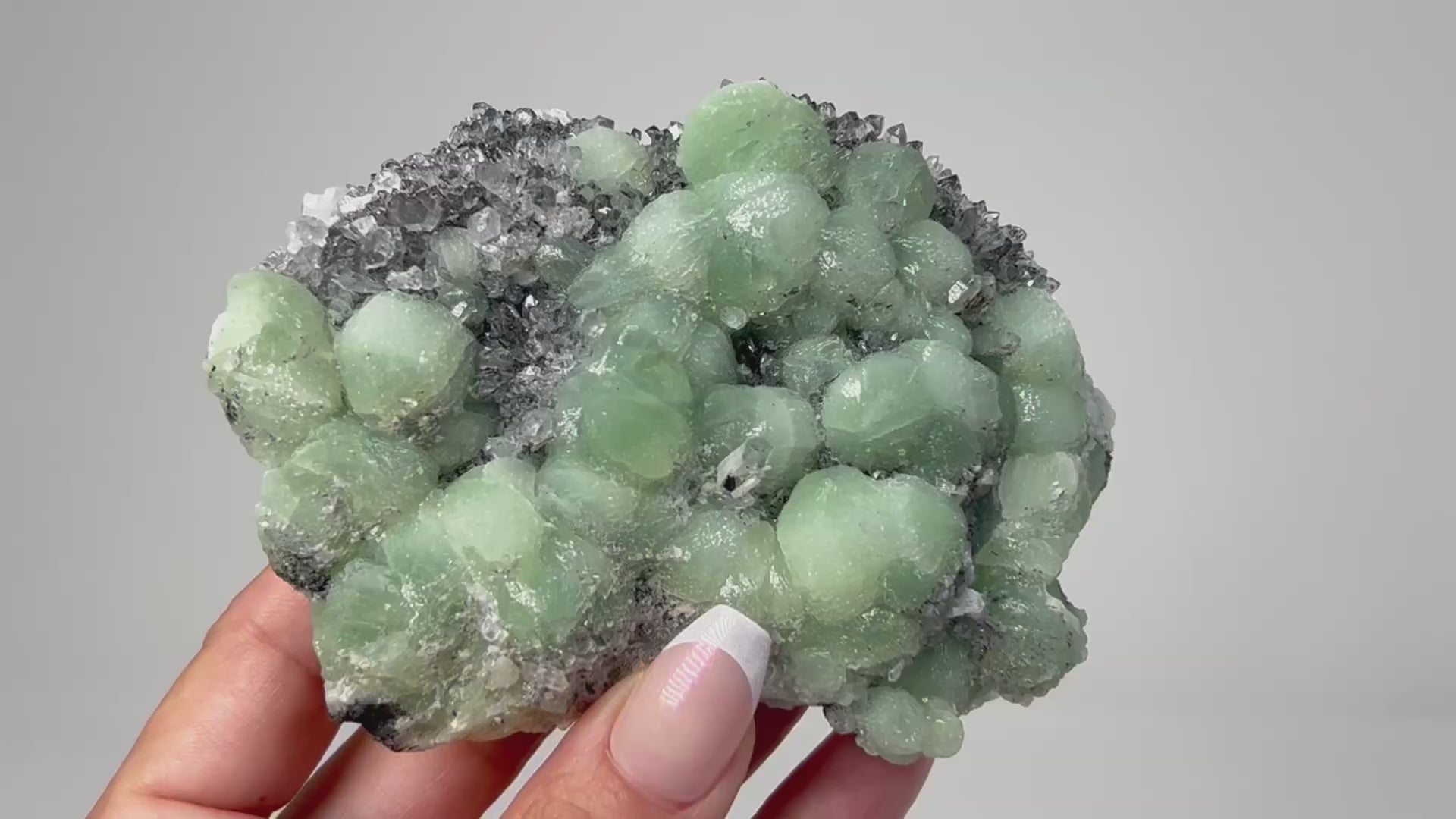 Prehnite on Quartz Cluster healing gemstone on table with white background.