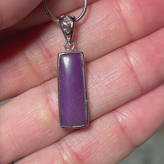 Video of hand holding a Sugilite Sterling Silver Pendant on a silver chain with floral background.