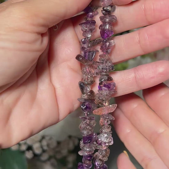 Hands holding a multi-colored Super 7 Chip Bead Bracelet for meditation and energy work with white background