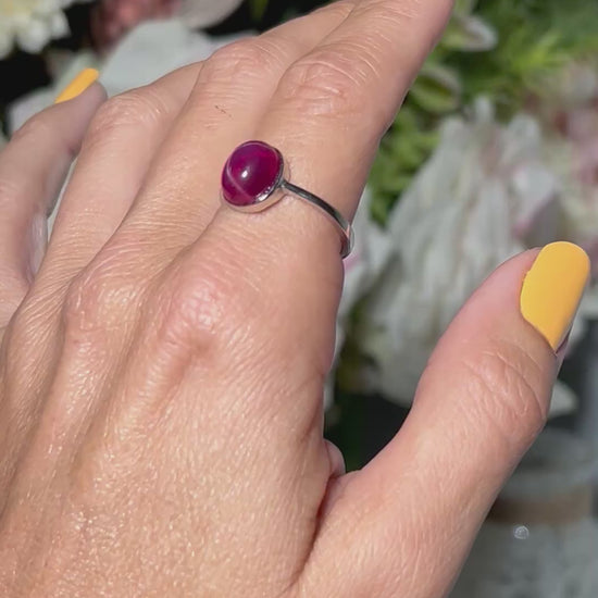 Hand wearing a Star Ruby and Sterling Silver Ring with floral background.