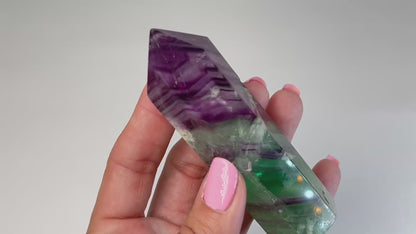 Video of hand holding a Rainbow Fluorite Tower gemstone with white background.