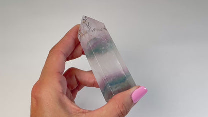 Video of hand holding a Dendritic Fluorite Tower gemstone with white background.